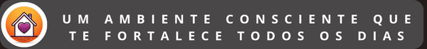 Banner horizontal cinza escuro com o texto em letras brancas: "UM AMBIENTE CONSCIENTE QUE TE FORTALECE TODOS OS DIAS". À esquerda, um círculo branco contém o desenho de uma casa com um coração roxo no centro, sobre um fundo gradiente alaranjado. O banner possui cantos arredondados.